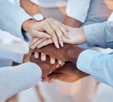 stock image of people touching each others hands in a team huddle