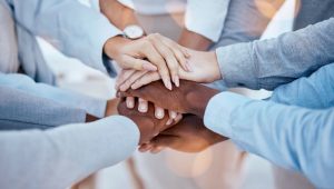 stock image of people touching each others hands in a team huddle