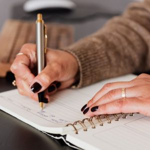 stock photo of female with painted nails writing in journal