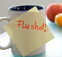 post it note saying flu shot on a coffee mug