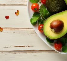 Valentine s Day concept Heart shaped avocado plate with roasted shrimp cherry tomatoes parsley on white wooden background