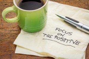 a green coffee cup on top of a napkin with the words focus on the positive written on it