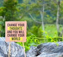 The words change your thoughts to change your world written on a sign with trees in the background