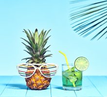 Tropical pineapple with cocktail on the beach with bight summer colors.