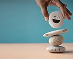 person stacking rocks with smiling face