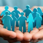 Two hands holding paper cut outs of a group of blue people.